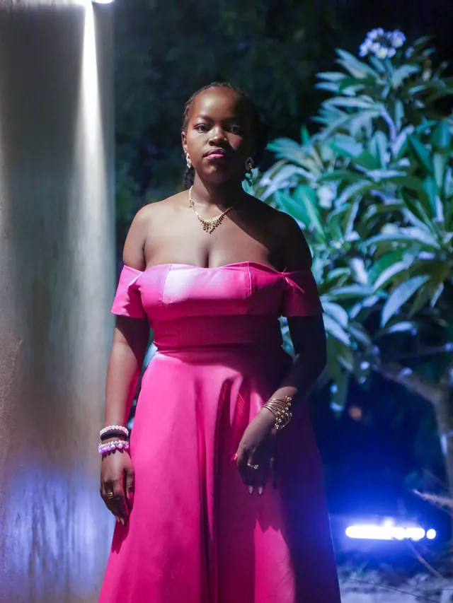 Festival performer in a vivid pink costume under stage lighting