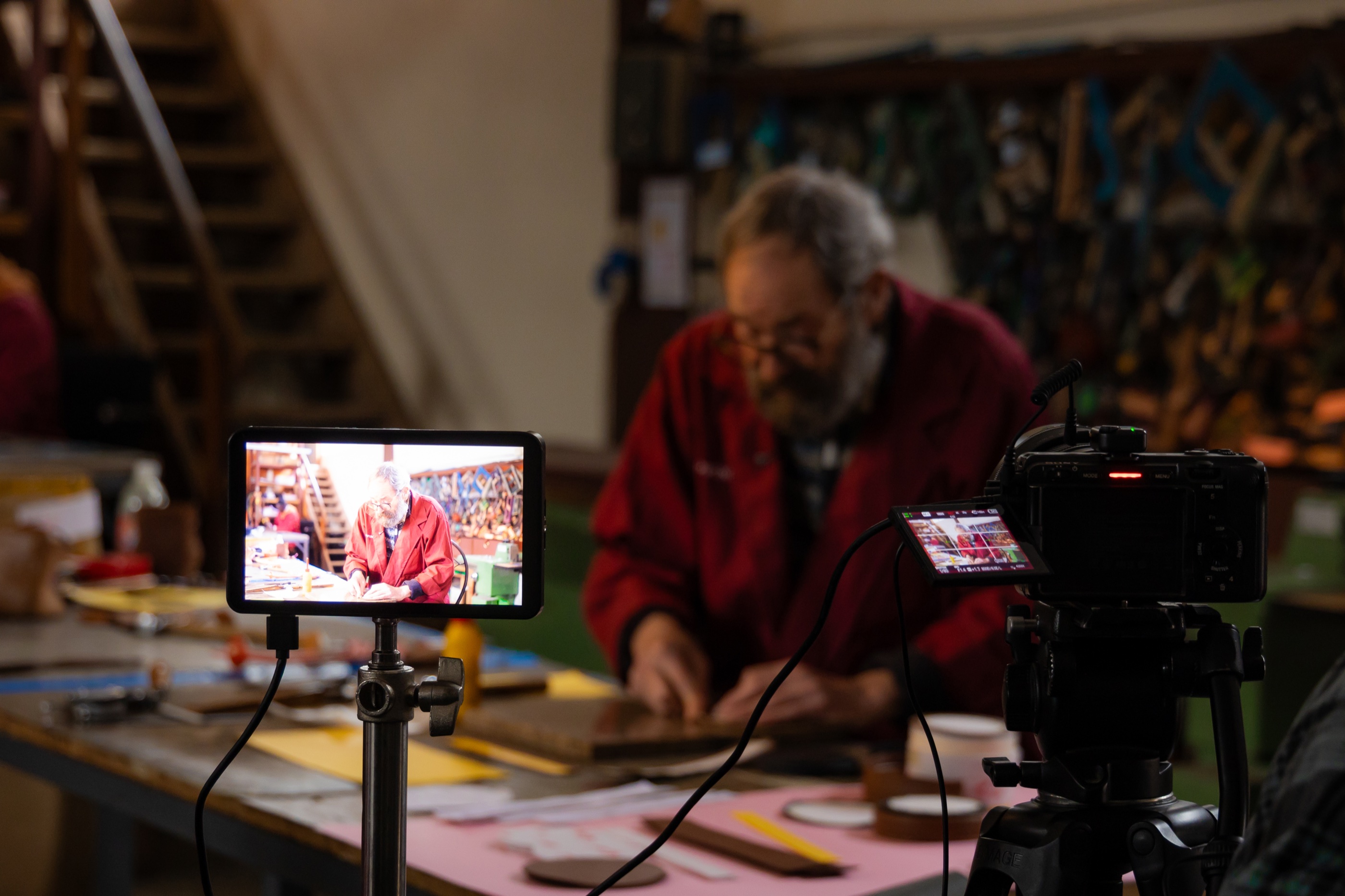 Behind-the-scenes camera and production monitor filming an artisan at work